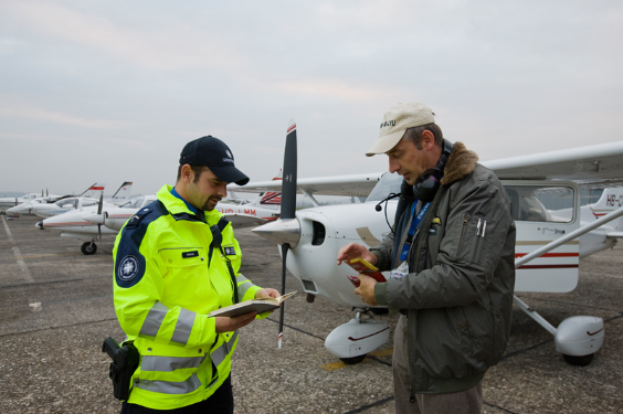 Una guardia di frontiera verifica un pilota sul campo d'aviazione vicino al suo aereo.